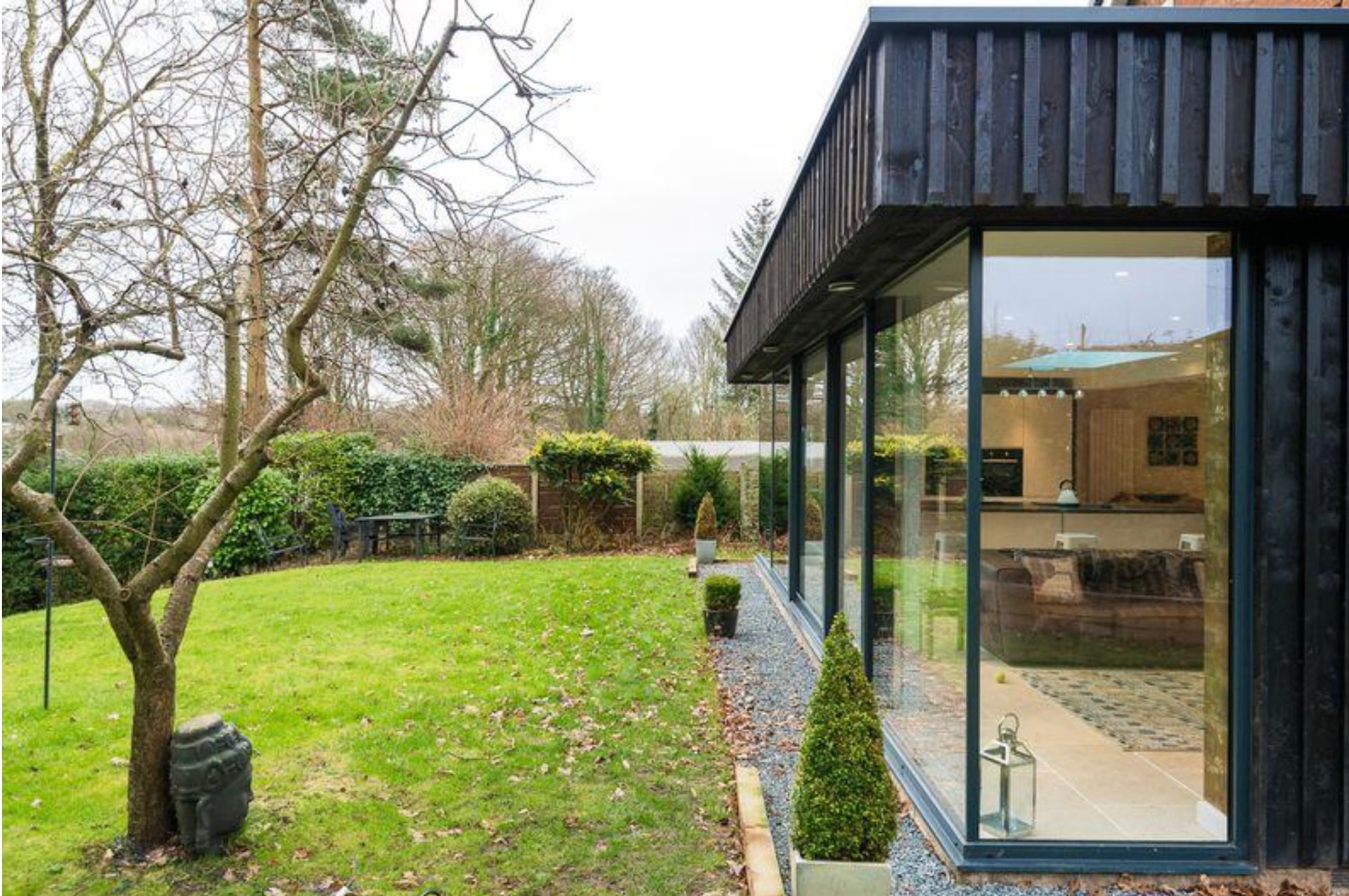 Black timber clad rear extension with floor-to-ceiling glazing overlooking the garden