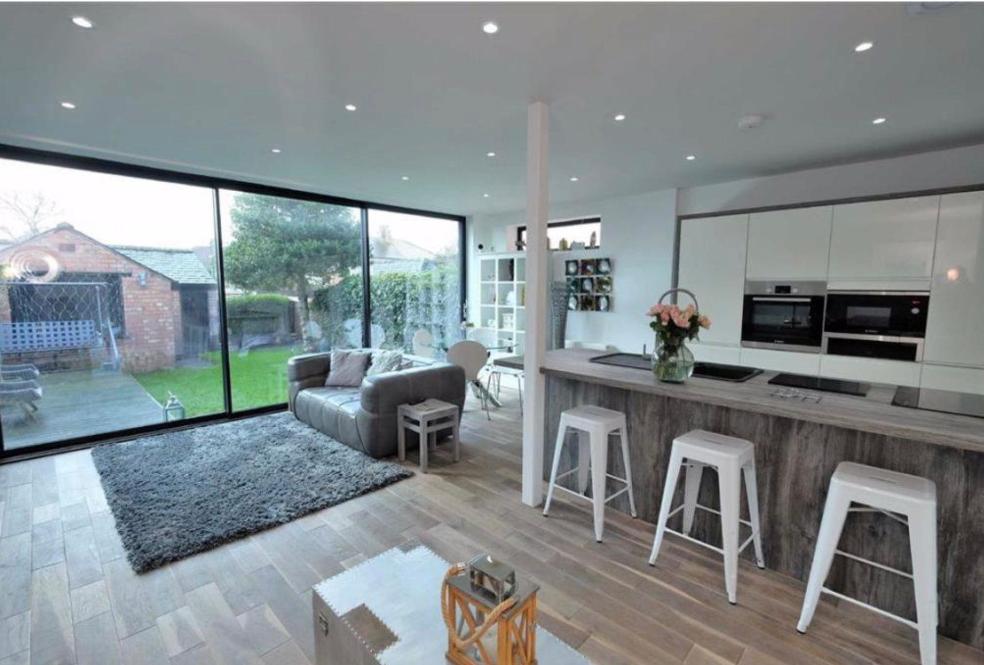 Open-plan kitchen and living space with island and full-height glazing onto the garden