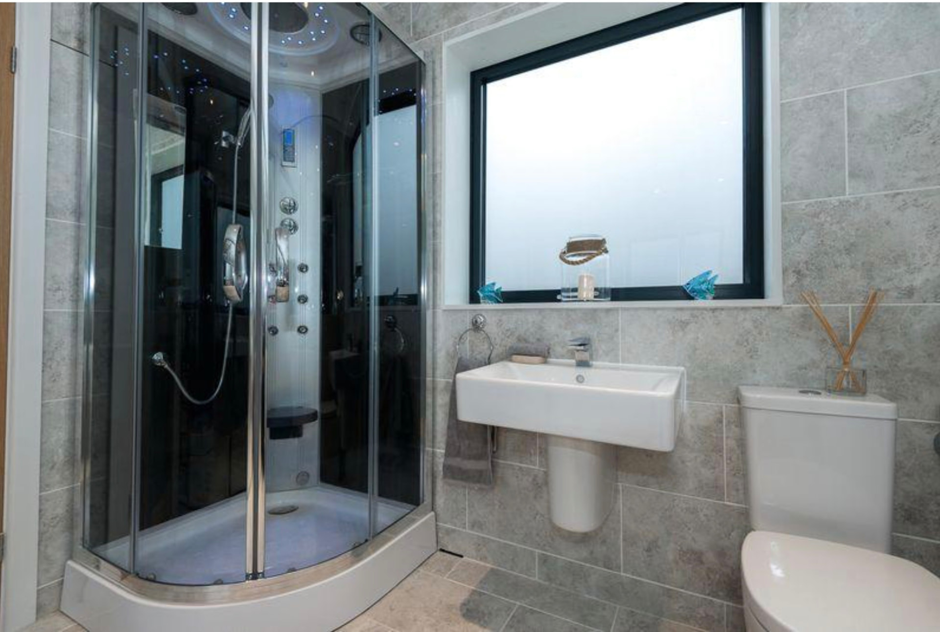 Grey tiled shower room with picture window and wall hung basin