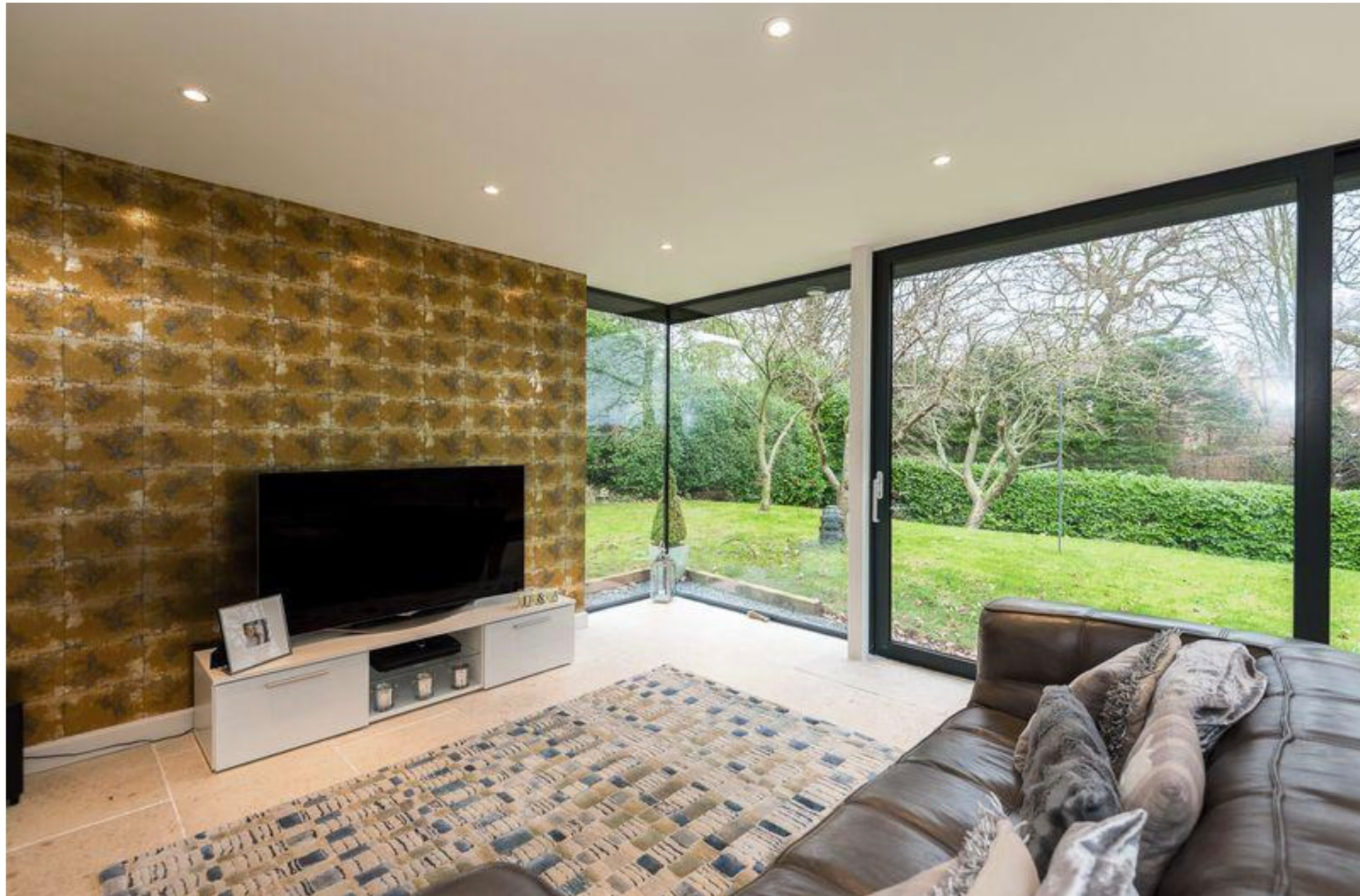 Living area with feature wall and frameless glazed corner onto the garden