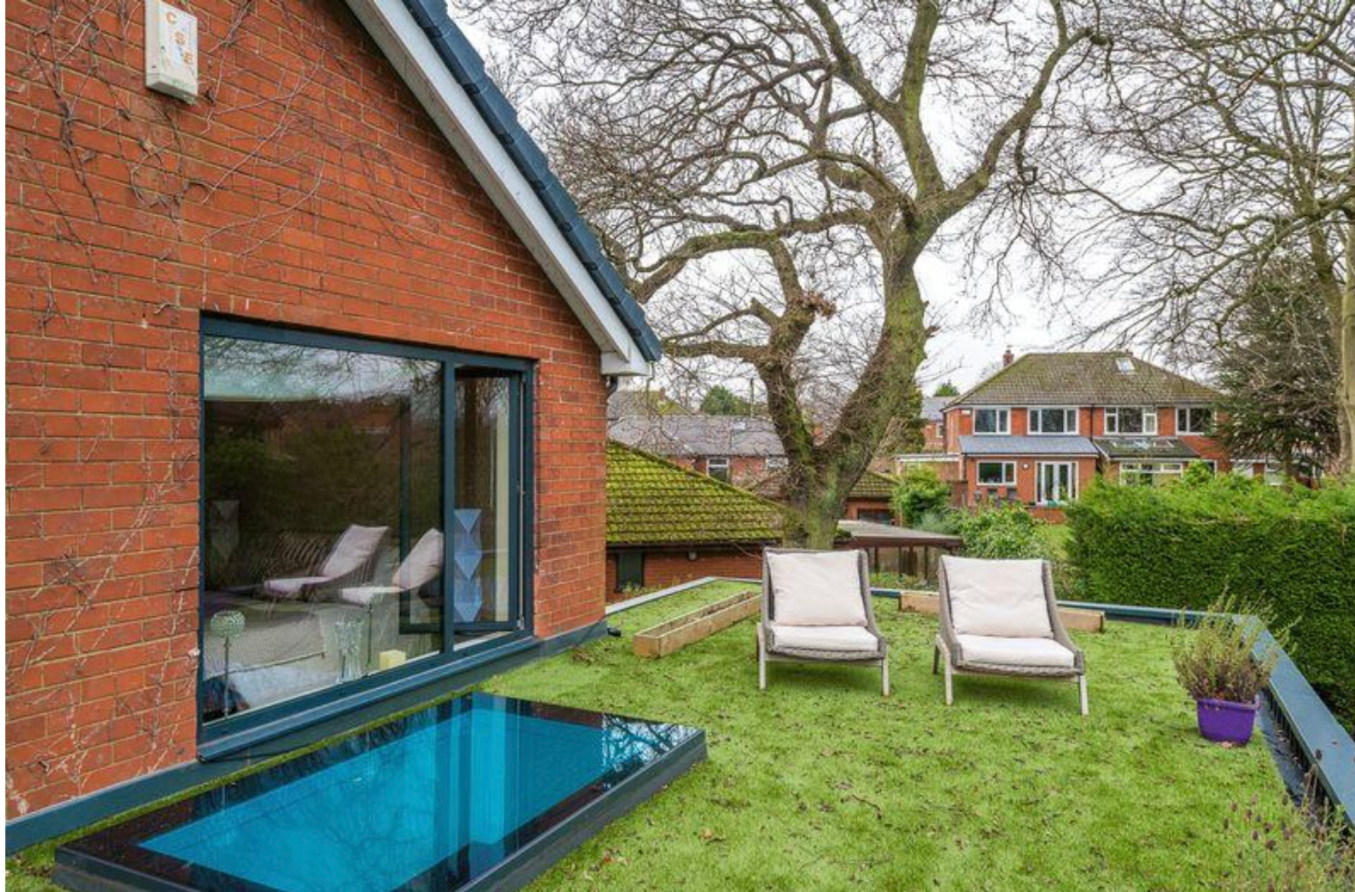 Brick elevation with sliding doors and a flush rooflight set into the lawn
